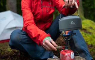 Woman boiling water in a kettle with the best backpacking stoves