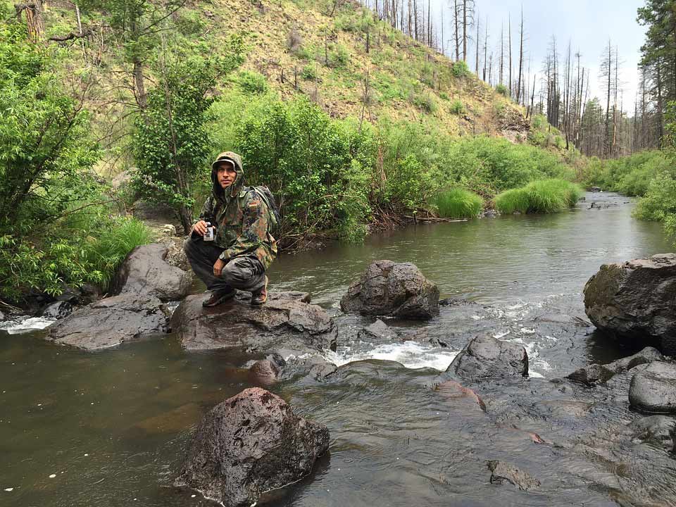 camper crouching in the middle of a stream