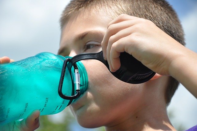 child drinking water from hiking bottle