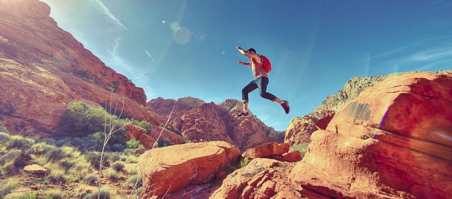 hiker jumping over rocks